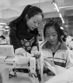 大英縣中等職業技術學校內，企業服裝技師正指導學生進行縫紉操作。
